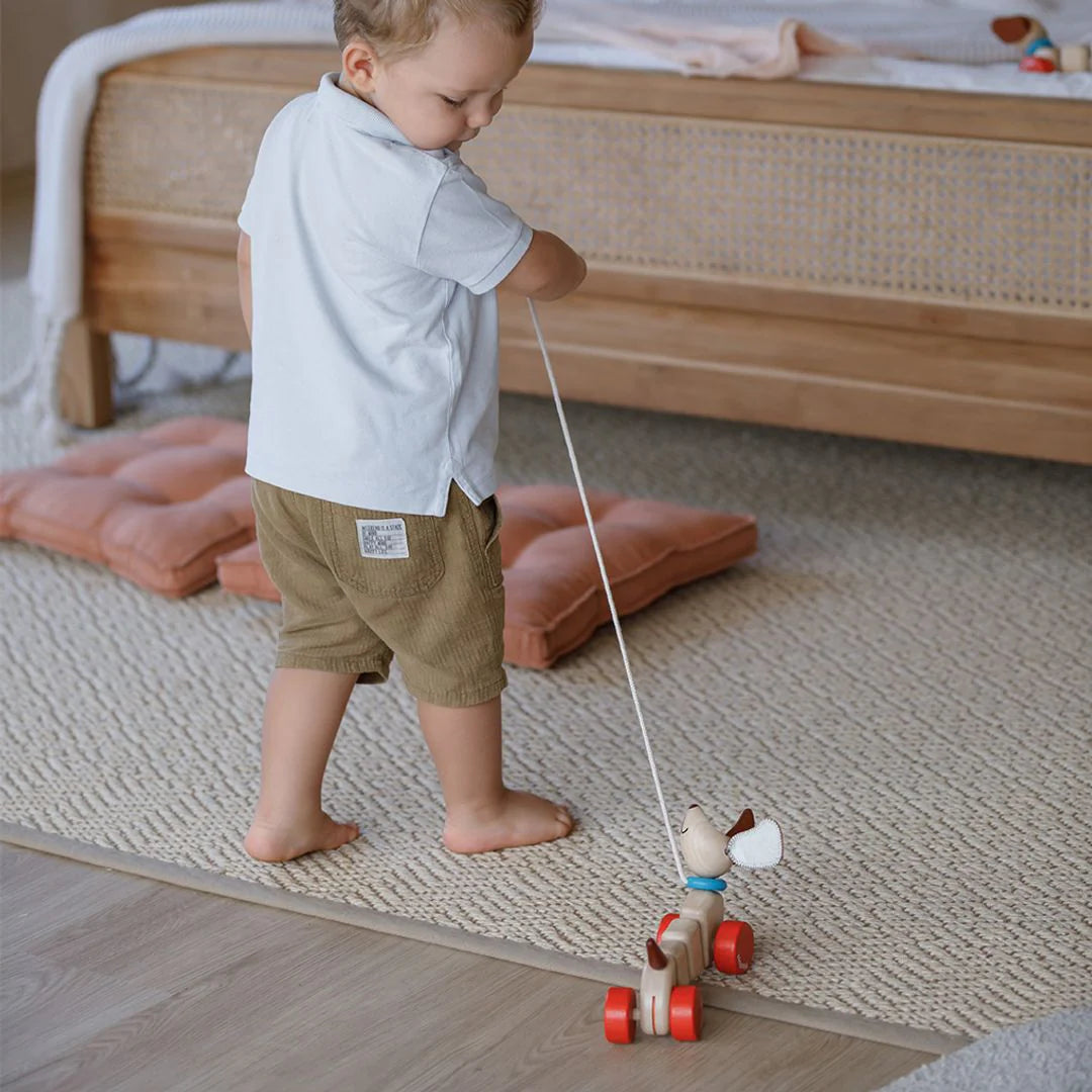 Child playing with a wooden toy on a carpeted floor