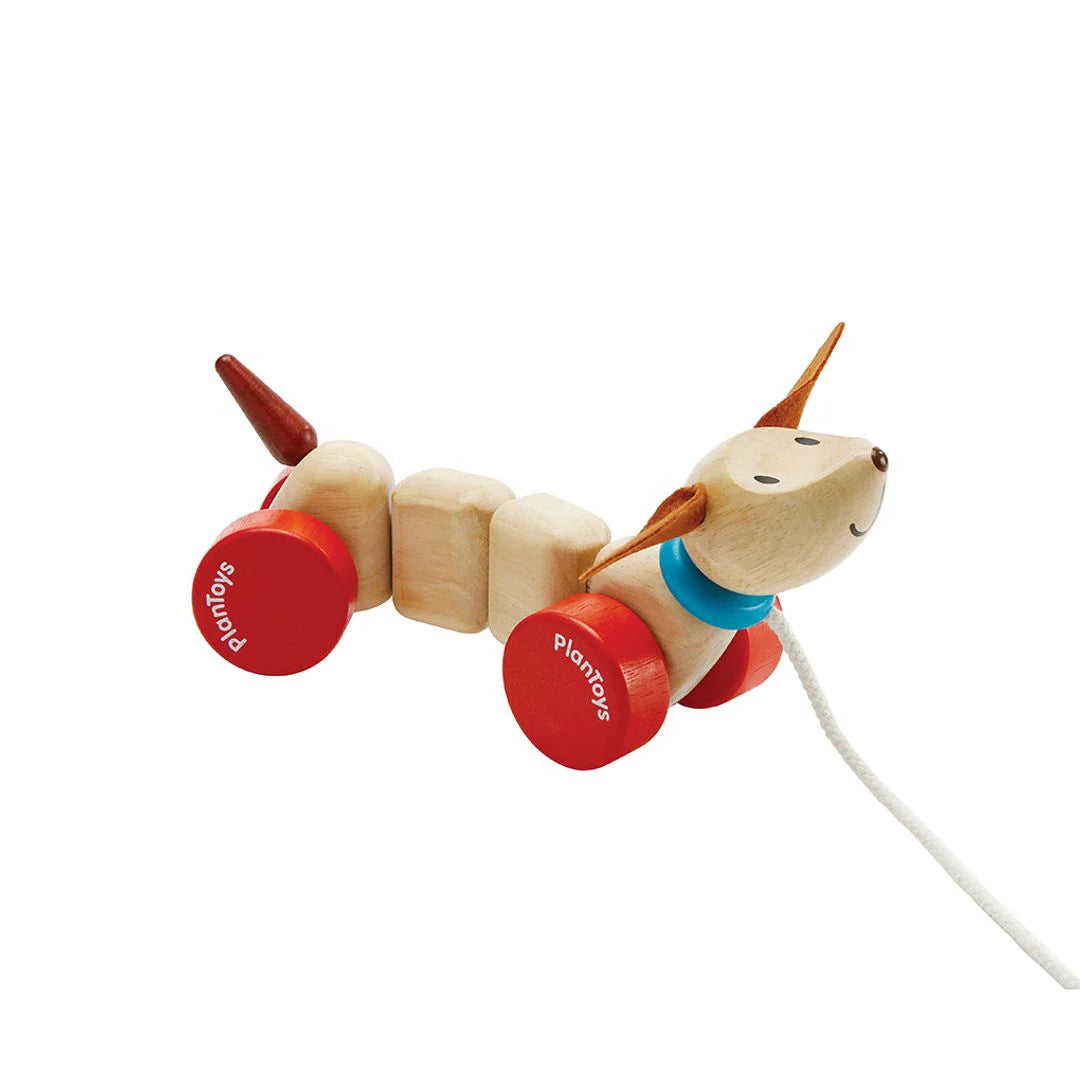 Wooden toy dog with red wheels on a white background