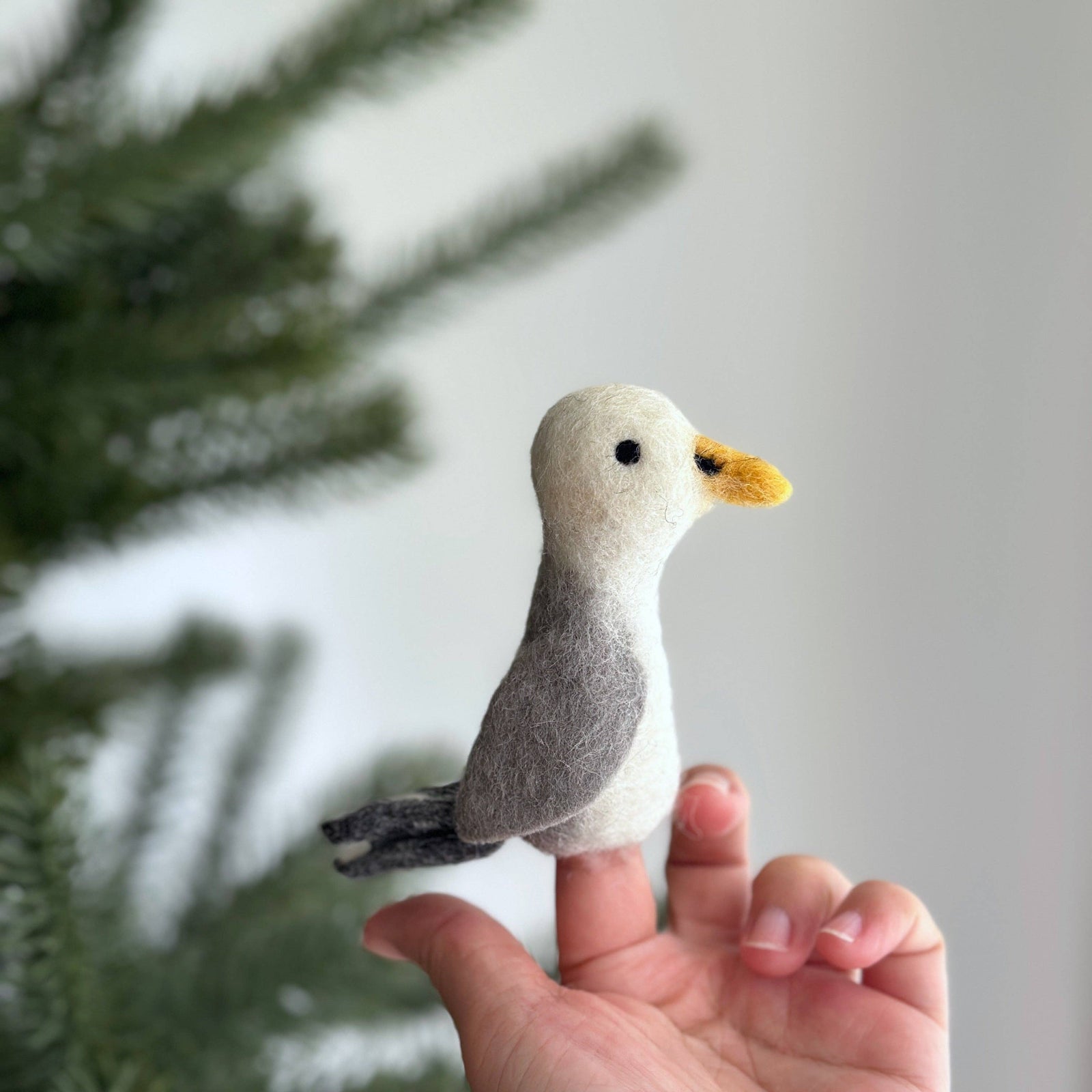 Small felt bird ornament held in a hand with a blurred natural background