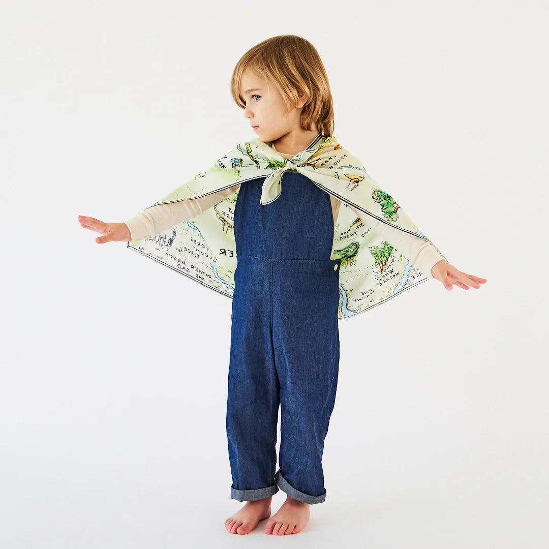 Child wearing a blue outfit with a patterned cape on a white background
