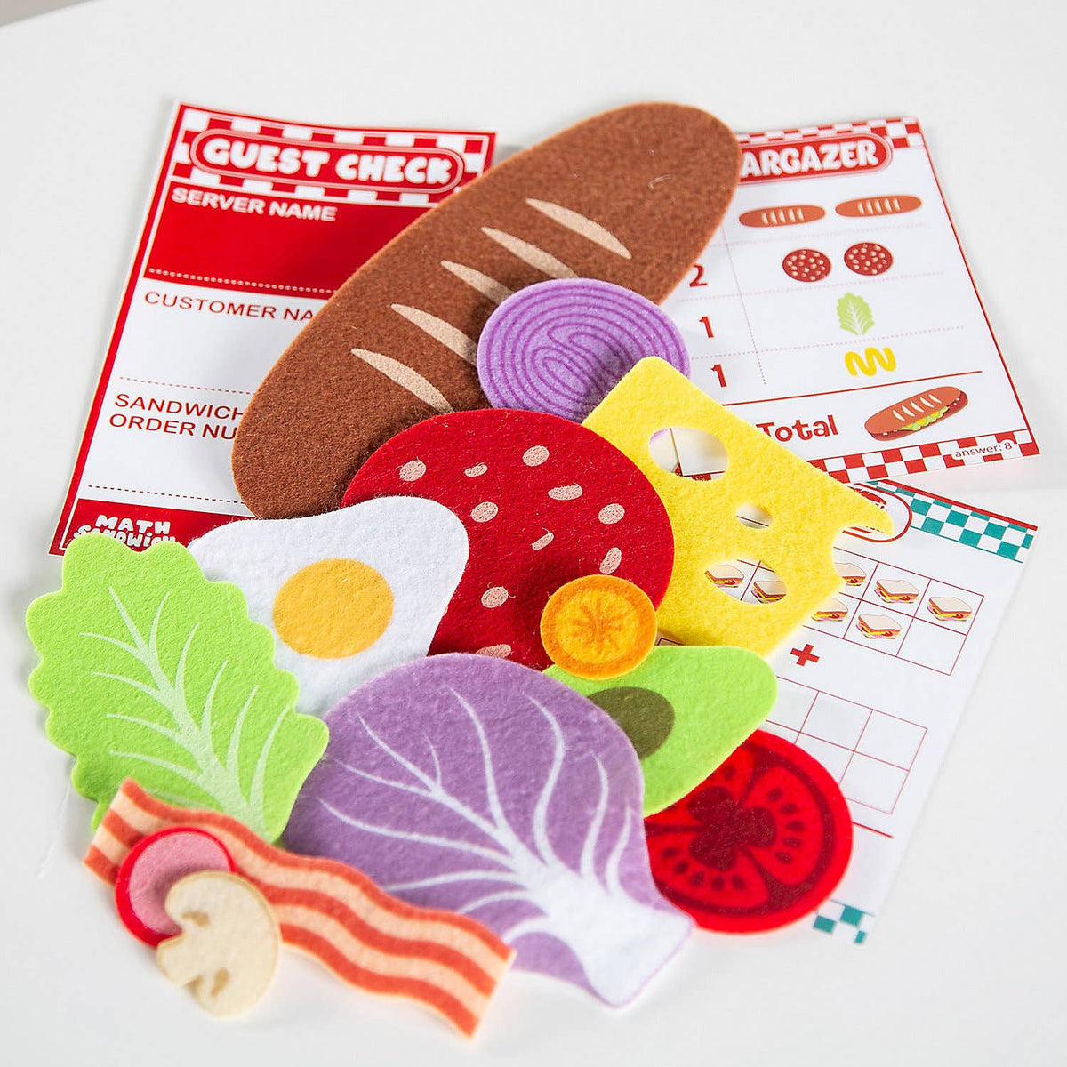 Colorful felt food items on a white surface with a restaurant-themed paper in the background.