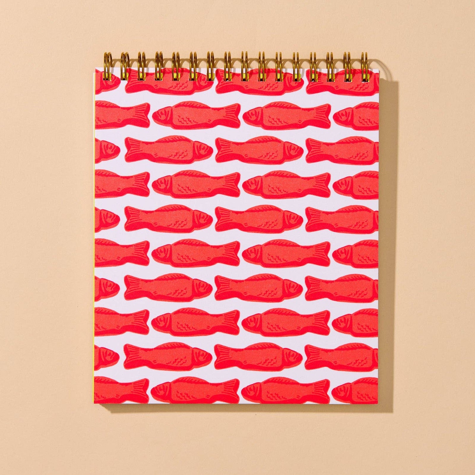 A spiral-bound children's activity book titled 'Doodle Book' with a bright yellow front cover, red fish illustrations, and gold wire binding, shown against a warm beige background.