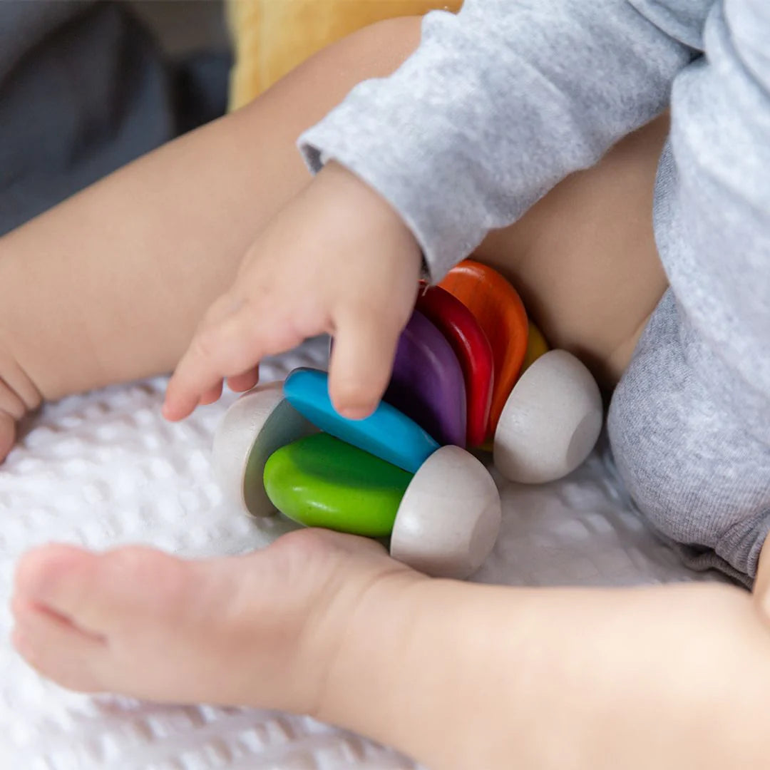 Baby playing with a colorful toy on a bed