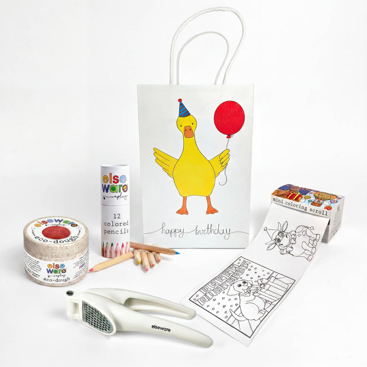 A birthday gift set from Elseware on a clean white background, featuring a white 'Happy Birthday' duck gift bag with a yellow duck illustration, a roll of multi-colored  paper a tube of colored pencils, wooden pencils, a coloring page, a paint palette, and a white dough press