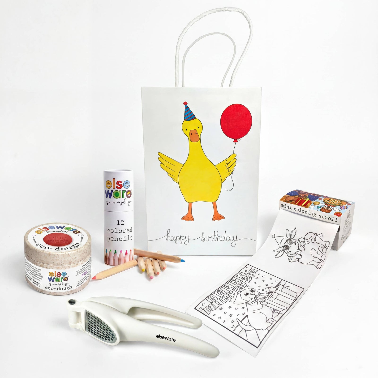 A birthday gift set from Elseware on a clean white background, featuring a white 'Happy Birthday' duck gift bag with a yellow duck illustration, a roll of multi-colored  paper a tube of colored pencils, wooden pencils, a coloring page, a paint palette, and a white dough press