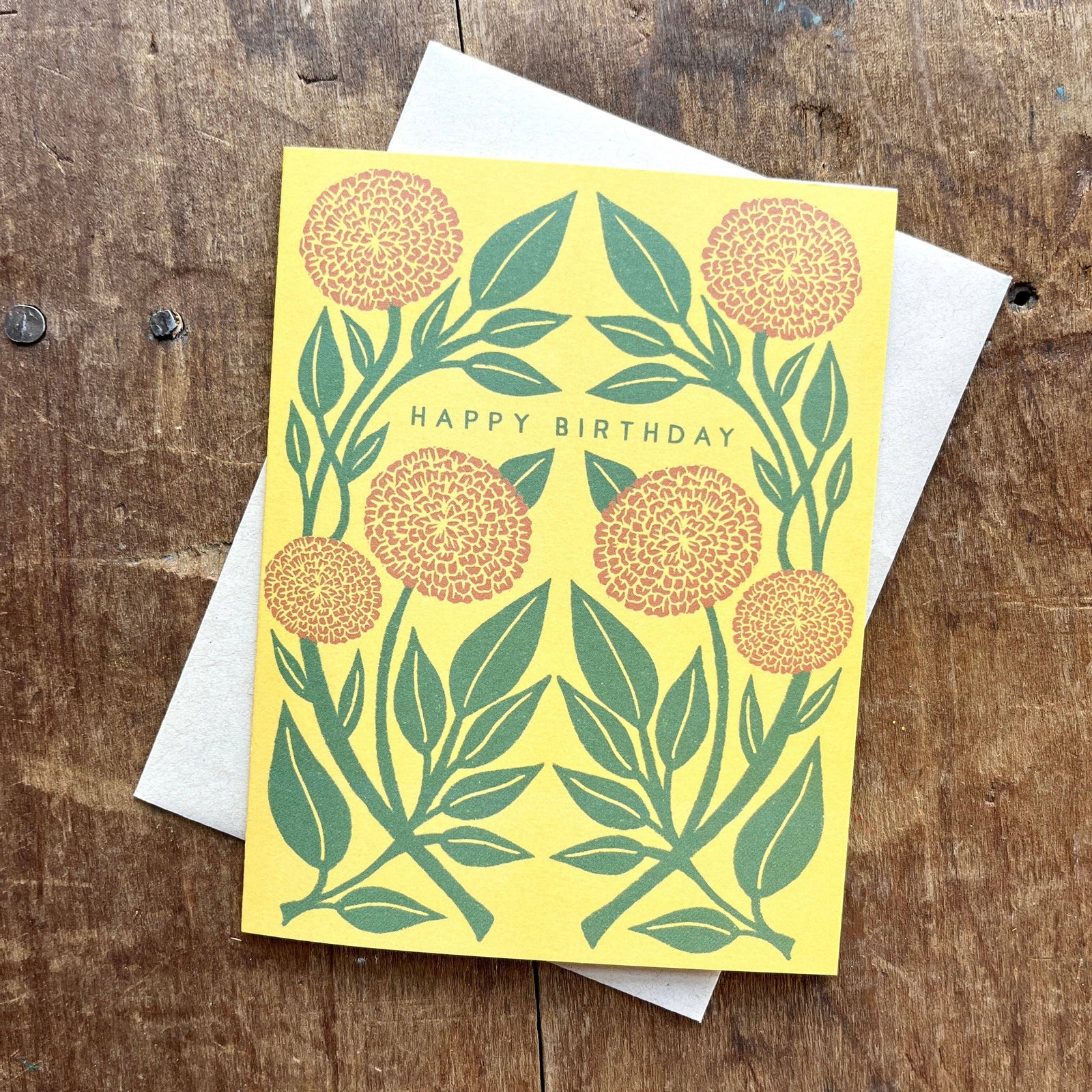 Yellow birthday card with floral design on a wooden surface