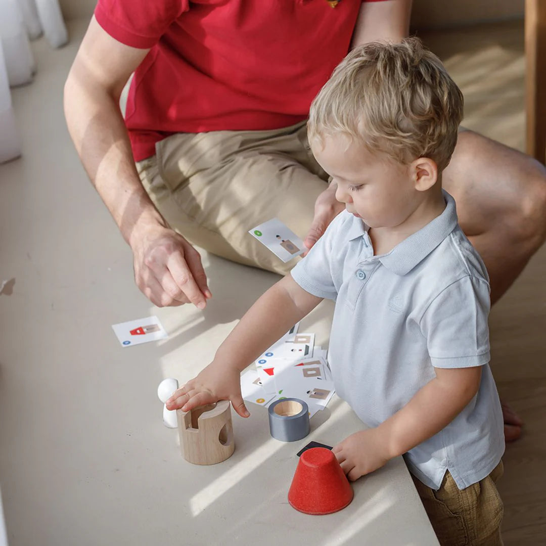 Child playing with toys on a table with an adult nearby