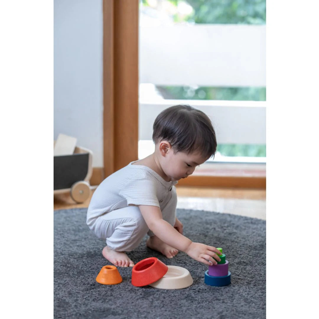 Child playing with colorful stacking toys on a carpeted floor.