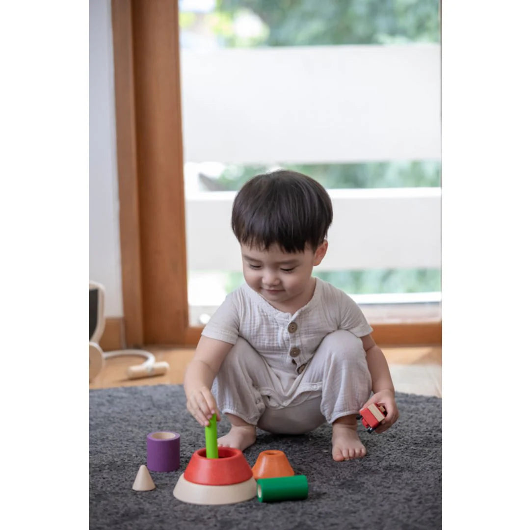 Child playing with colorful toys on a rug in a room with large windows.