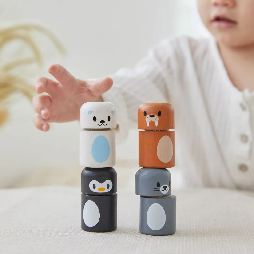 Child playing with stackable animal toys on a light surface