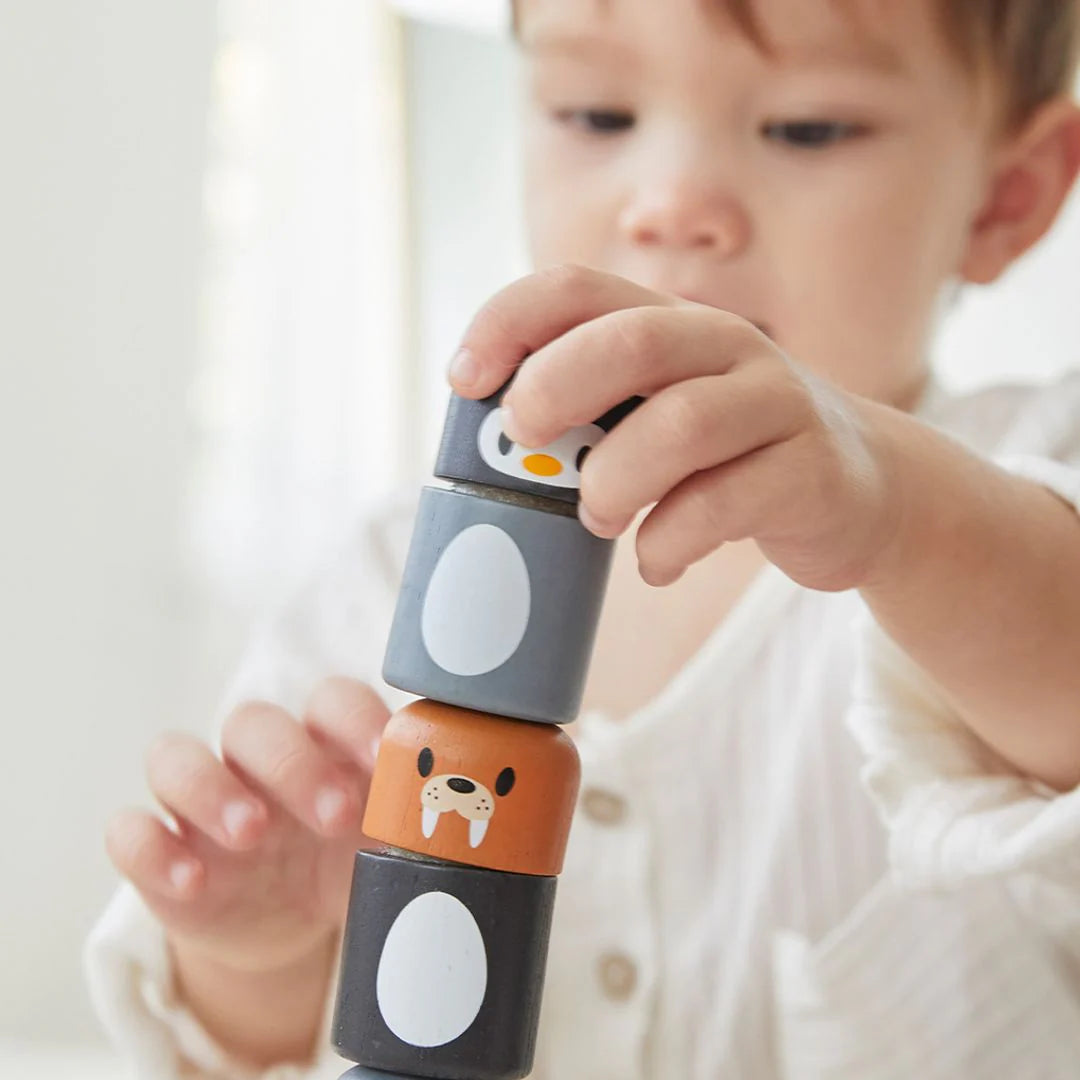 Child playing with stackable animal toys on a light surface