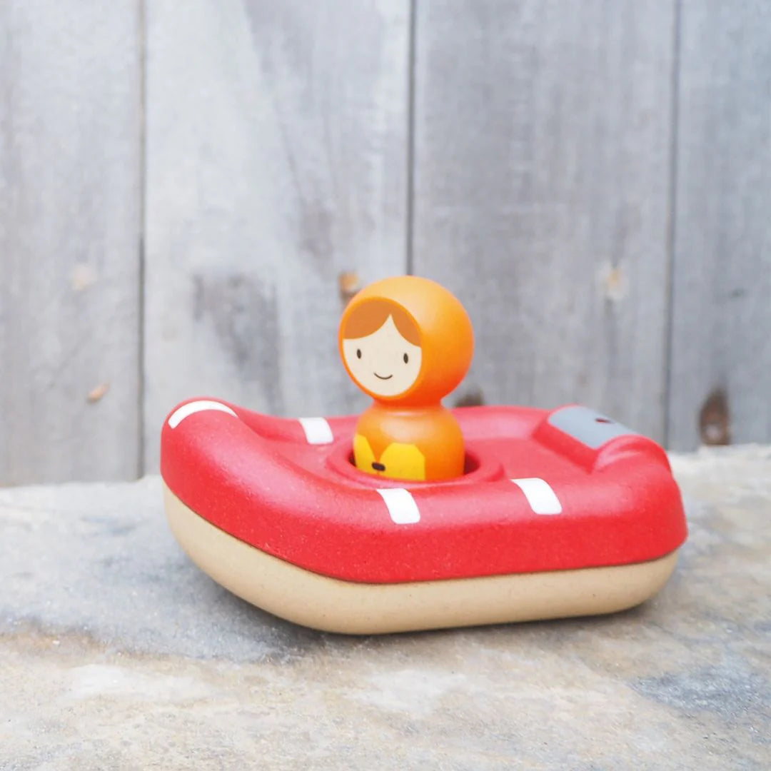 Toy lifeboat with a figure on a wooden surface