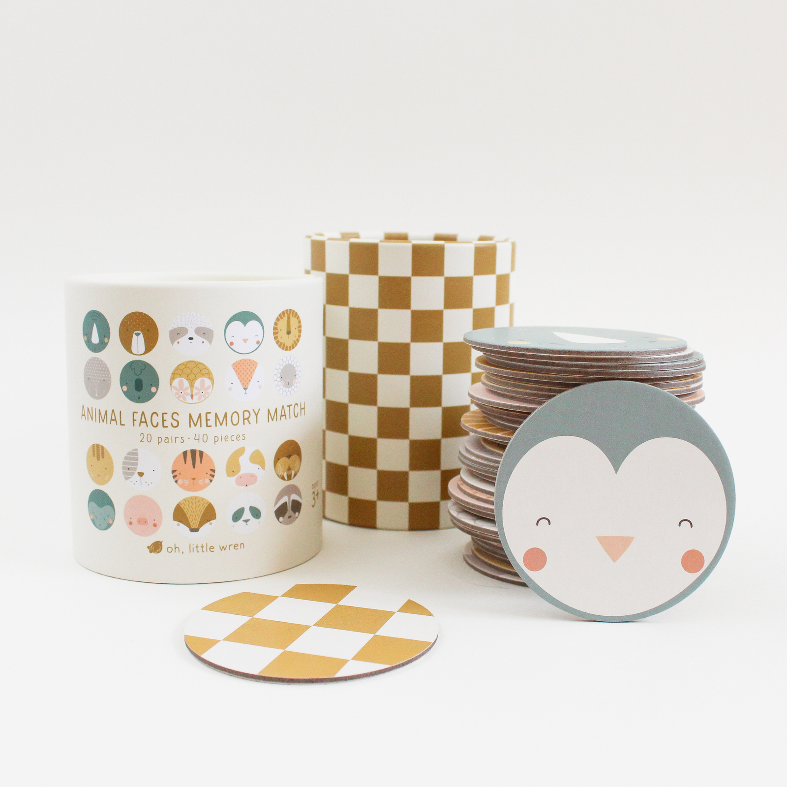 Children's memory game with animal face cards, storage canisters, and checkered mat on a white background