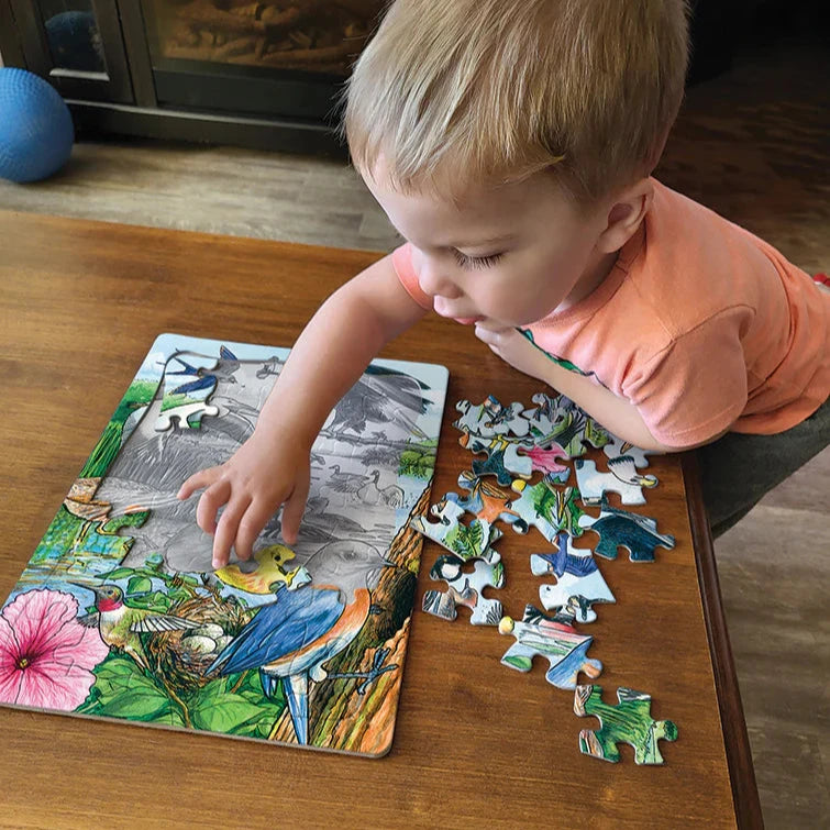 Child playing with a dinosaur puzzle on a wooden table.