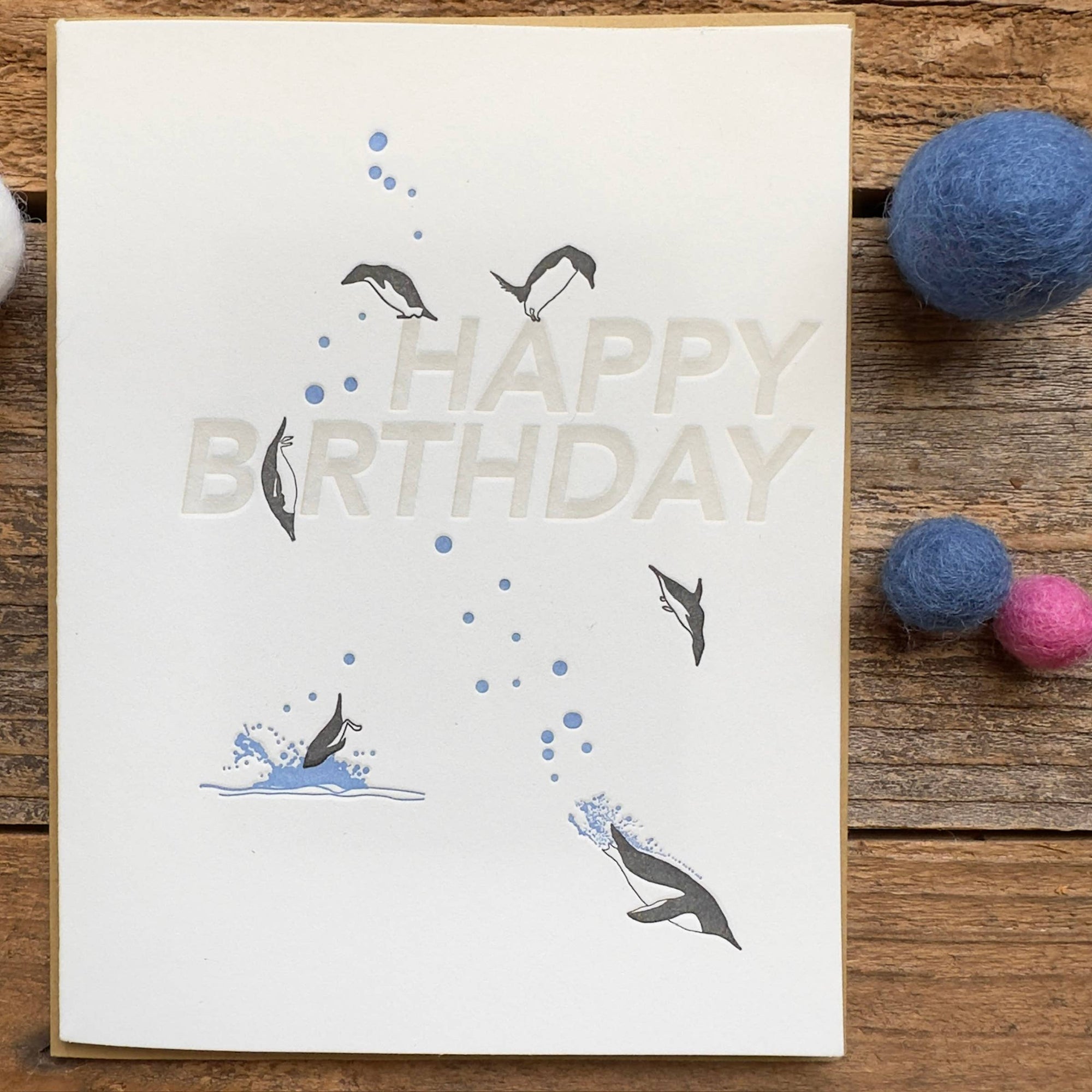 Birthday card with whale illustrations on a wooden surface