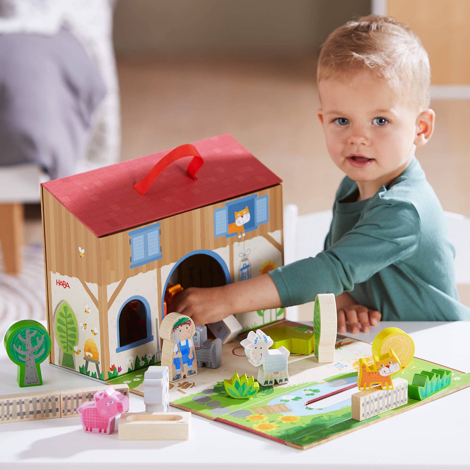 Toy farm set with animals and a barn in a cardboard box on a white background