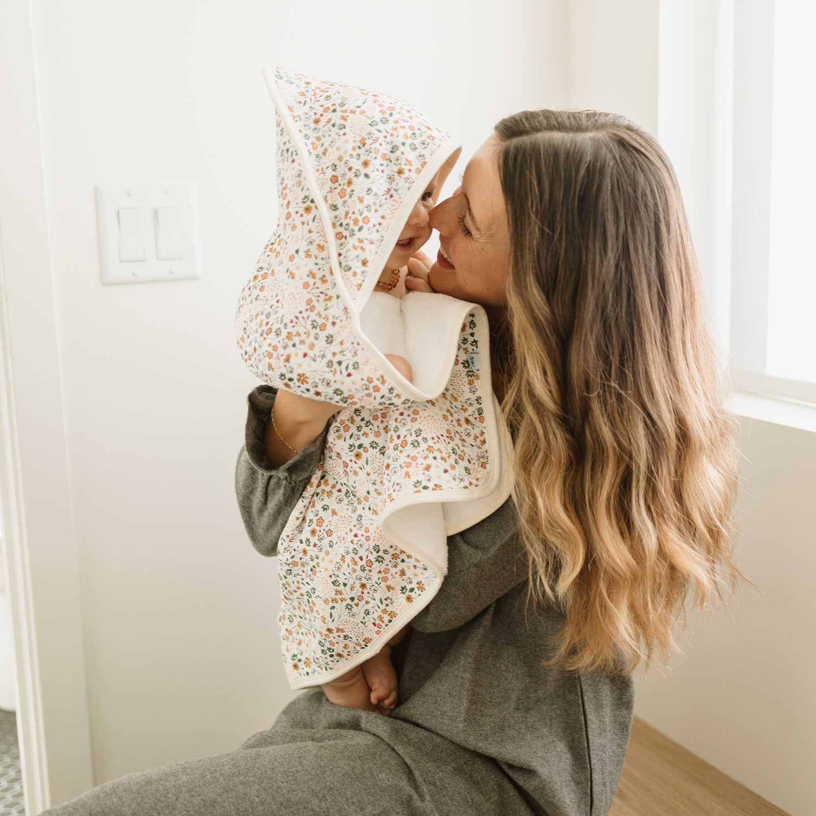 A infant towel with a multicolor floral print on the exterior and a soft white fleece interior, shown folded on a clean white background.