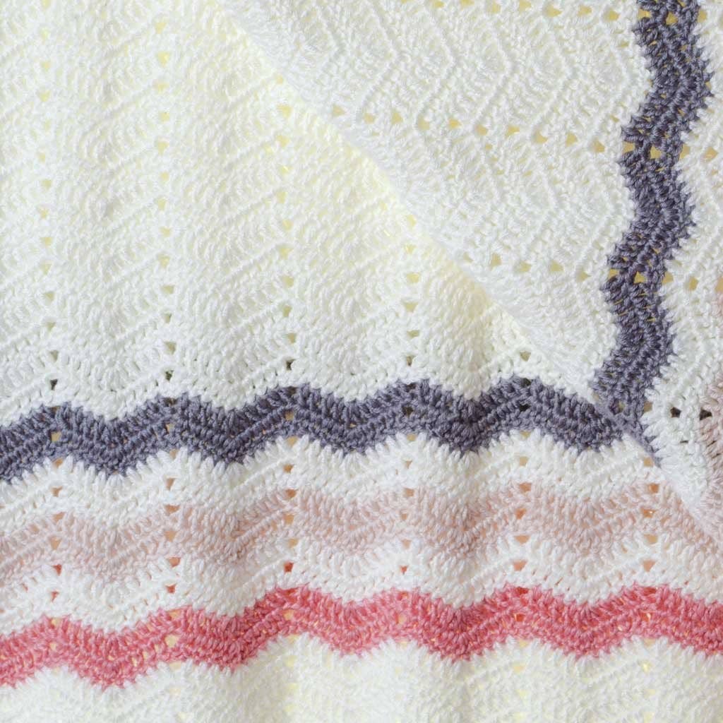 Close-up of a textured fabric with wavy purple and pink lines on a white background
