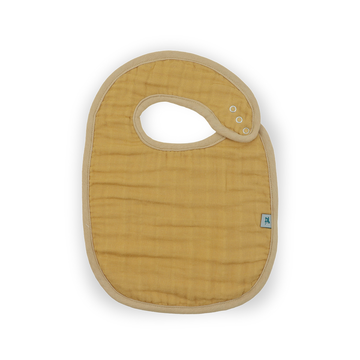 A mustard yellow muslin baby bib with a beige trim and a small blue brand tag, shown on a clean white background.