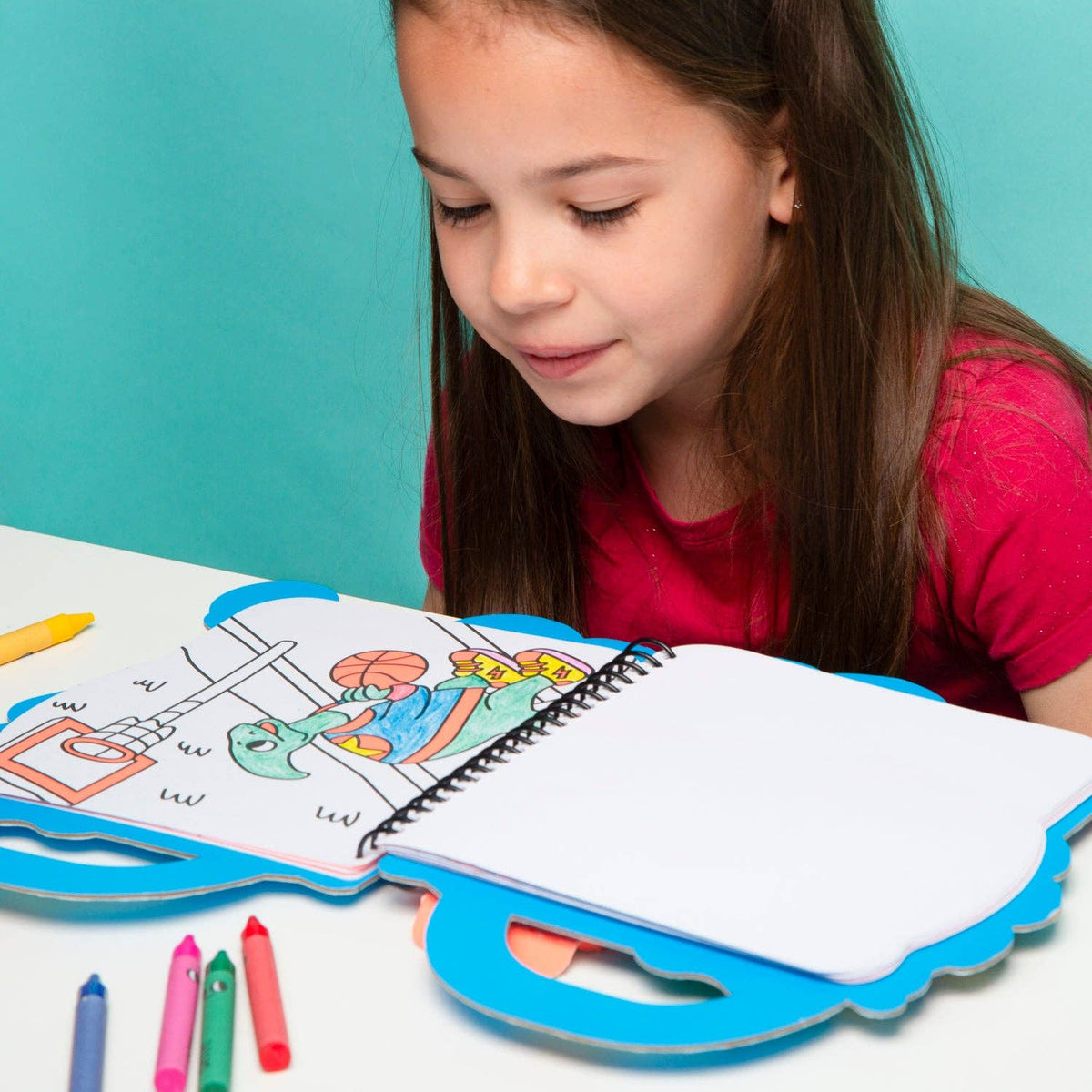 Child coloring in a book with crayons on a blue background
