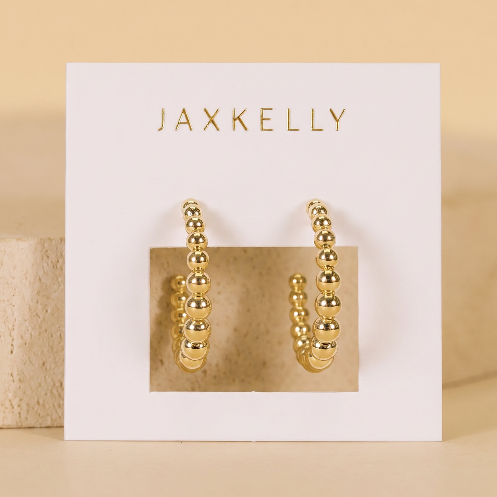 Gold hoop earrings on a Jaxkelly branded card with a beige background