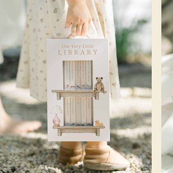 Product packaging labeled 'Our Very Little Library' held by a person outdoors.
