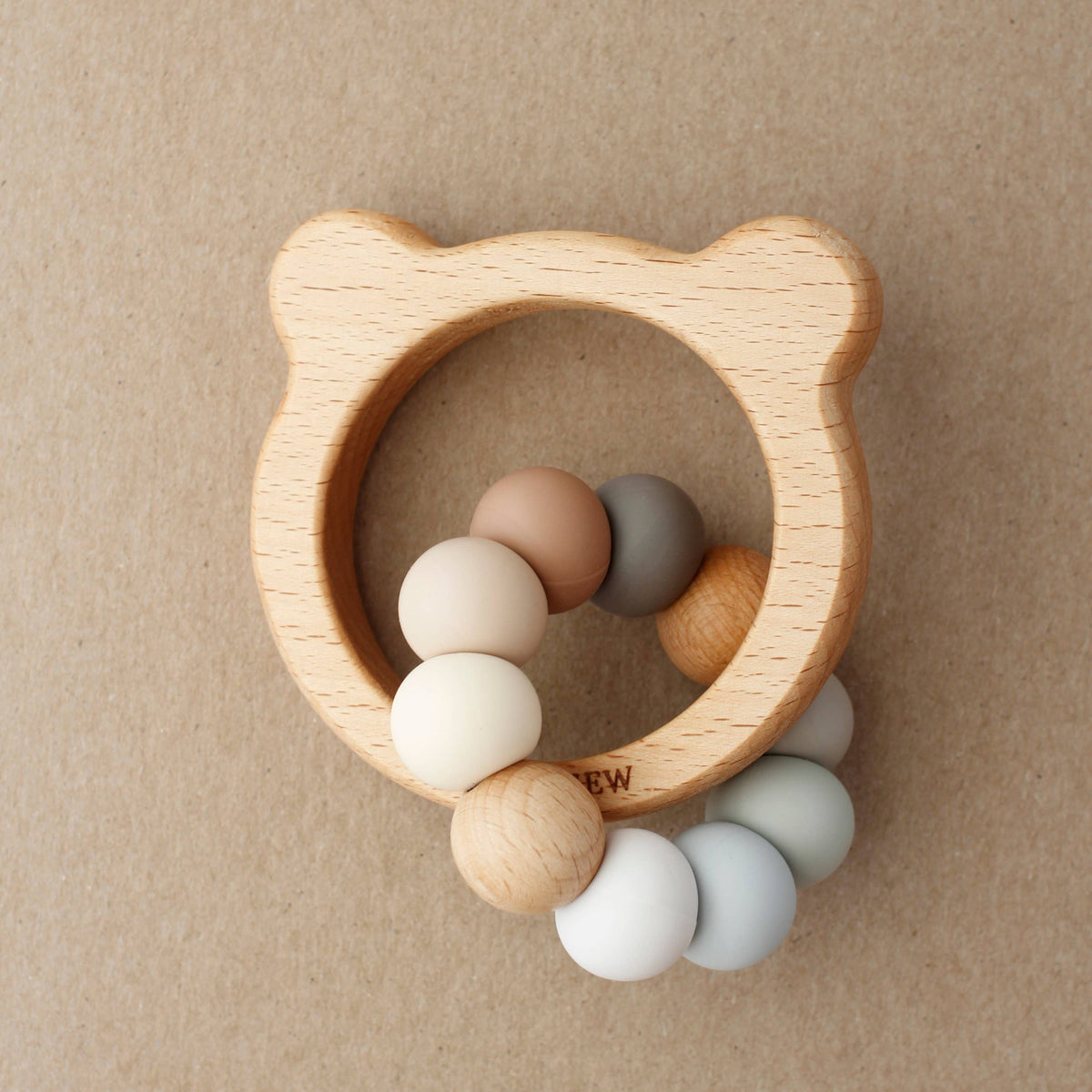 Wooden teething ring with colorful beads on a beige background