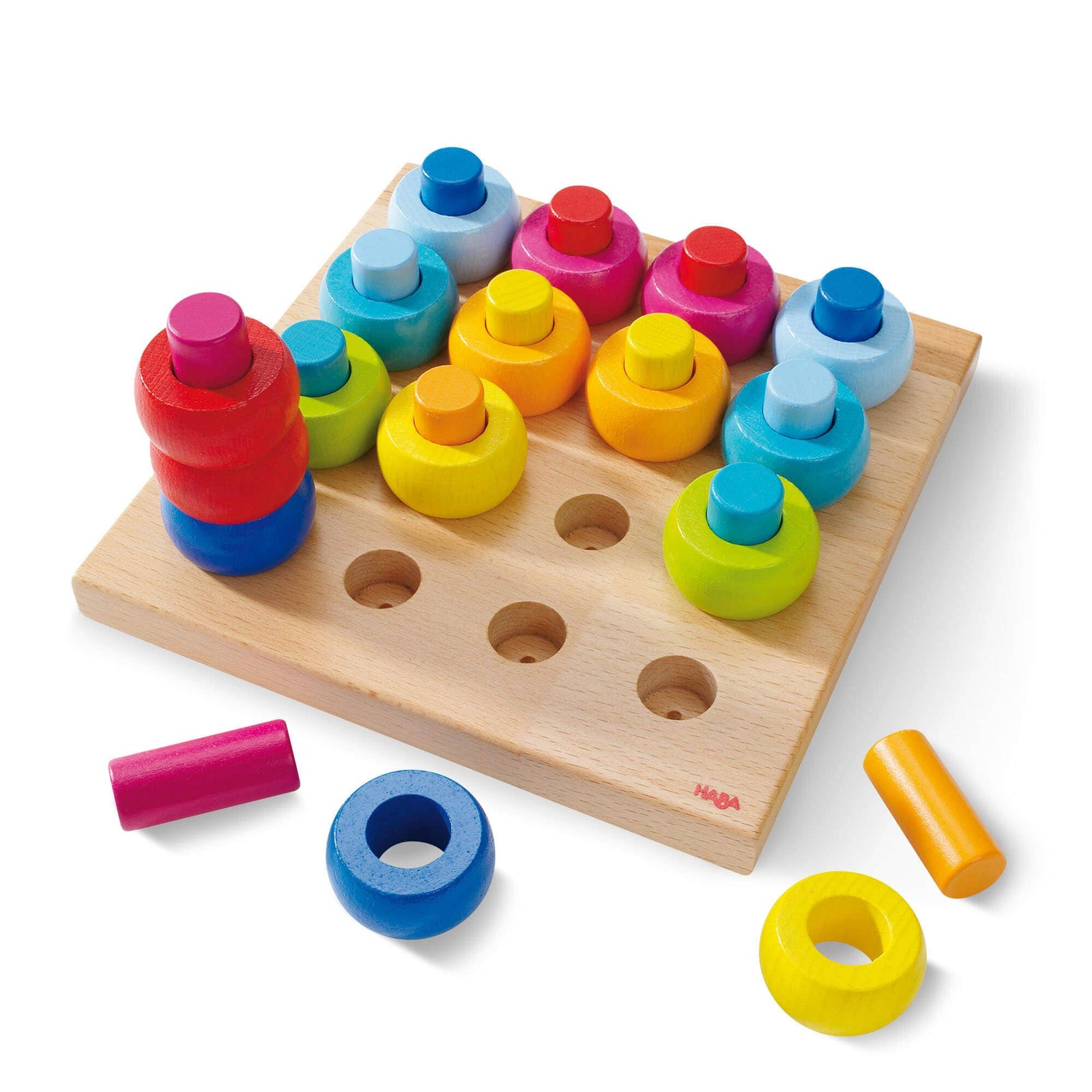 Colorful wooden puzzle toy on a wicker surface with child's hands interacting with it.