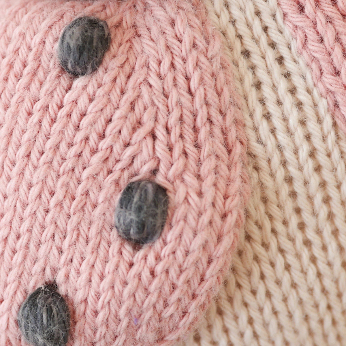 Close-up of pink yarn with gray bobbins on a textured background