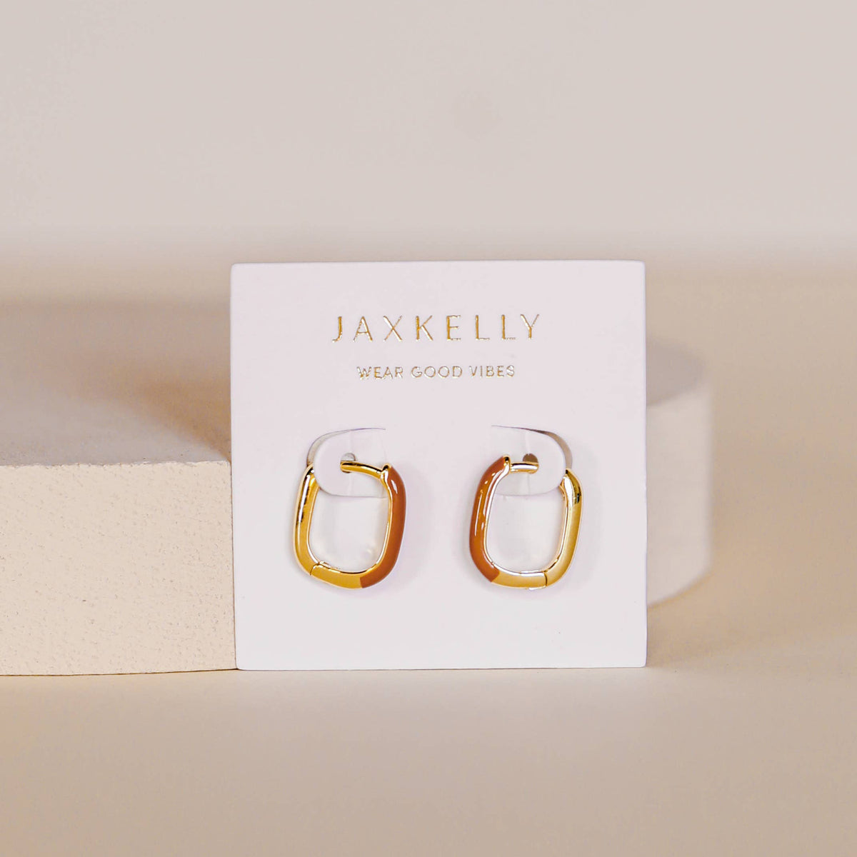 Gold hoop earrings on a Jax Kelley branded card with a beige background