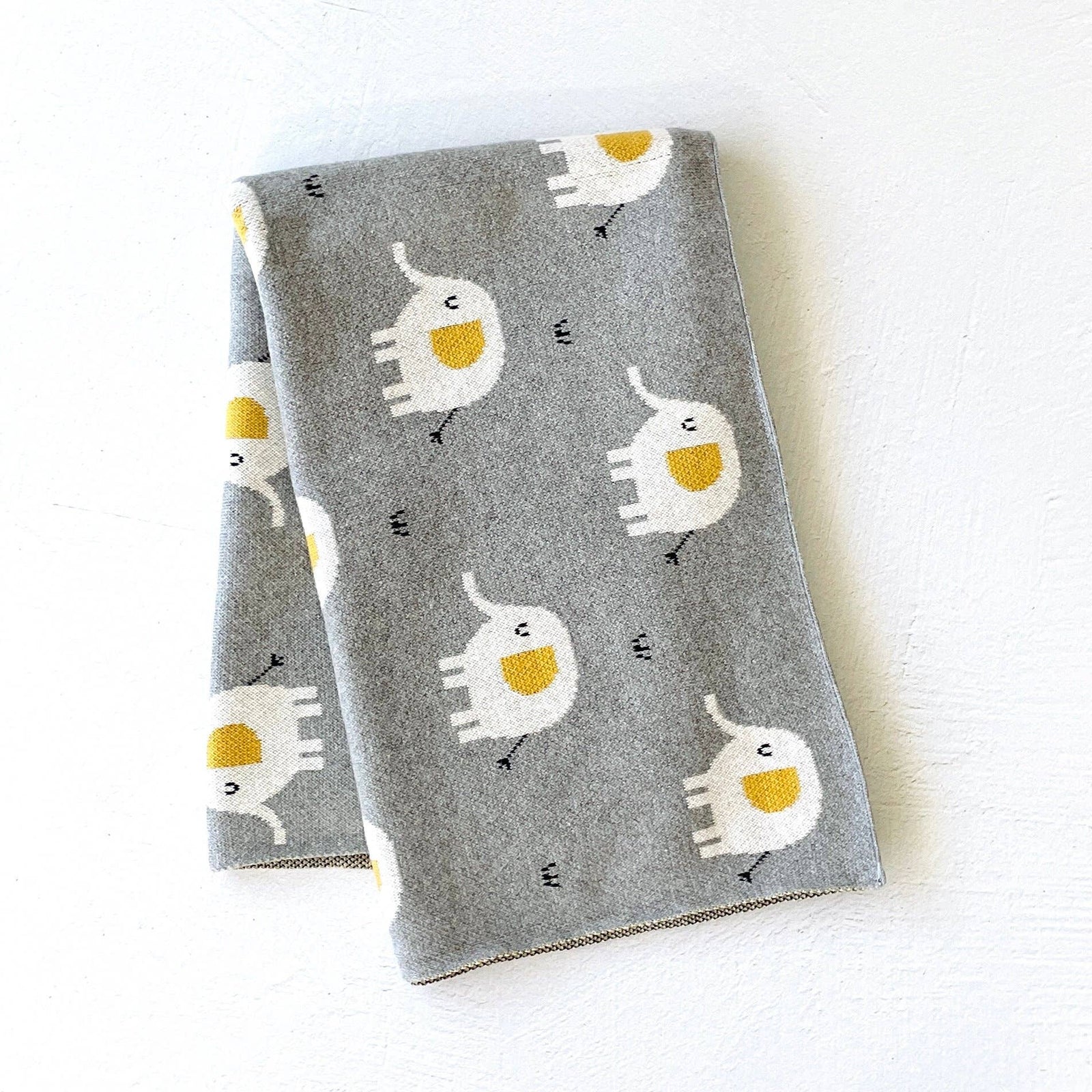 Gray blanket with white and yellow cat pattern on a white background