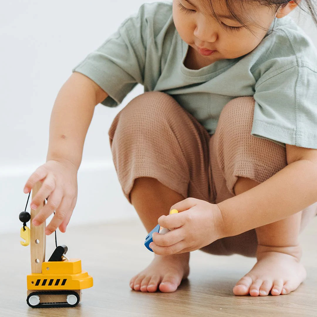 Set of toy construction vehicles including a crane, dump truck, and bulldozer on a white background