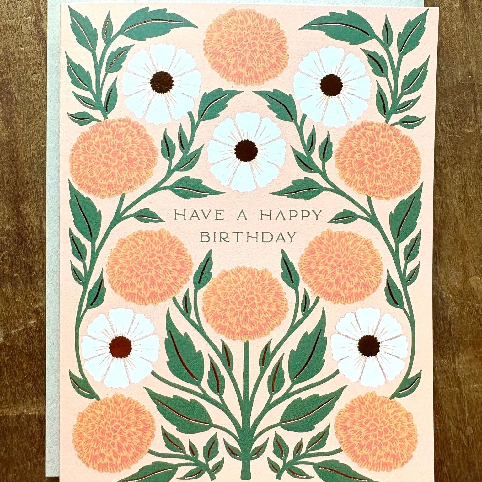 Floral birthday card with peach and white flowers on a wooden surface