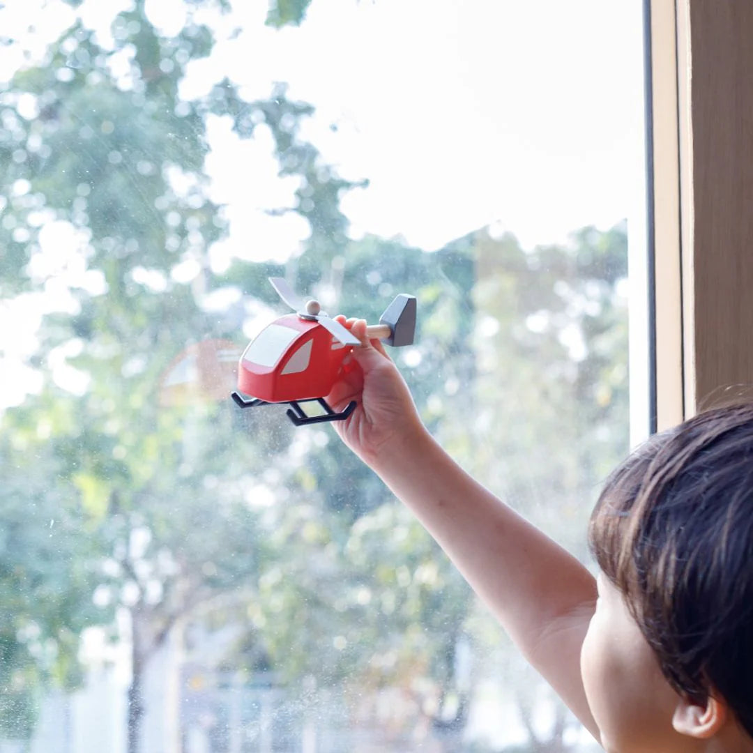 Red toy helicopter with a white stripe on a white background