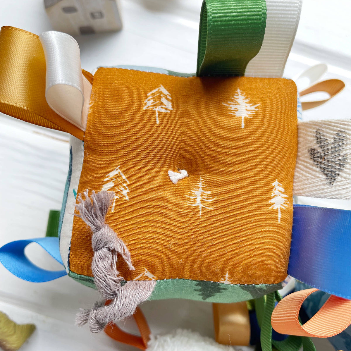 Fabric square with tree pattern attached to a ribbon on a textured surface