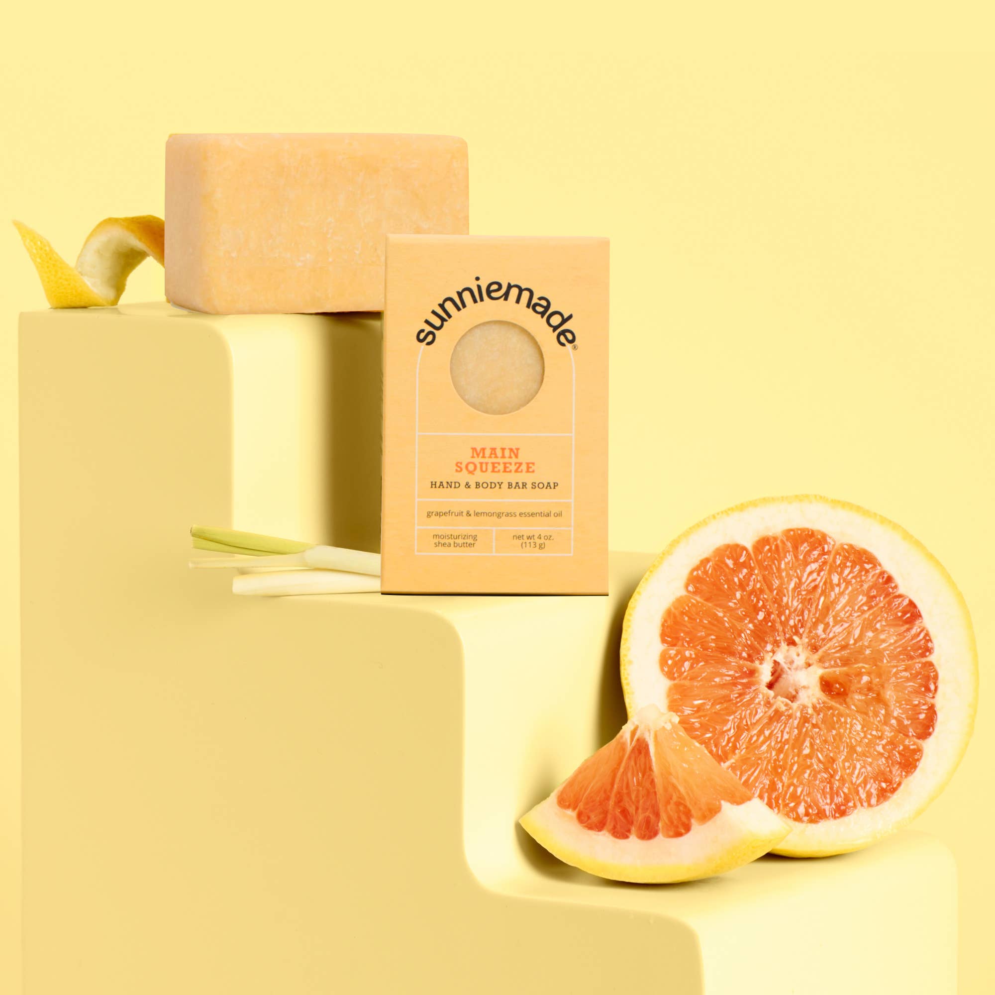 Sunniemade grapefruit soap bar and packaging on a yellow background with a sliced grapefruit.