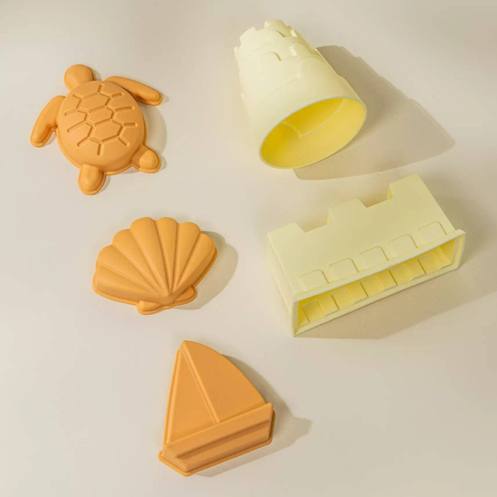 Set of silicone molds shaped like a turtle, shell, sailboat, and house on a light background