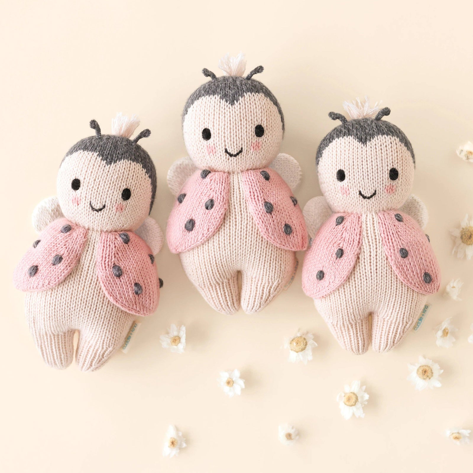 Knitted ladybug toy with pink wings and black spots on a white background