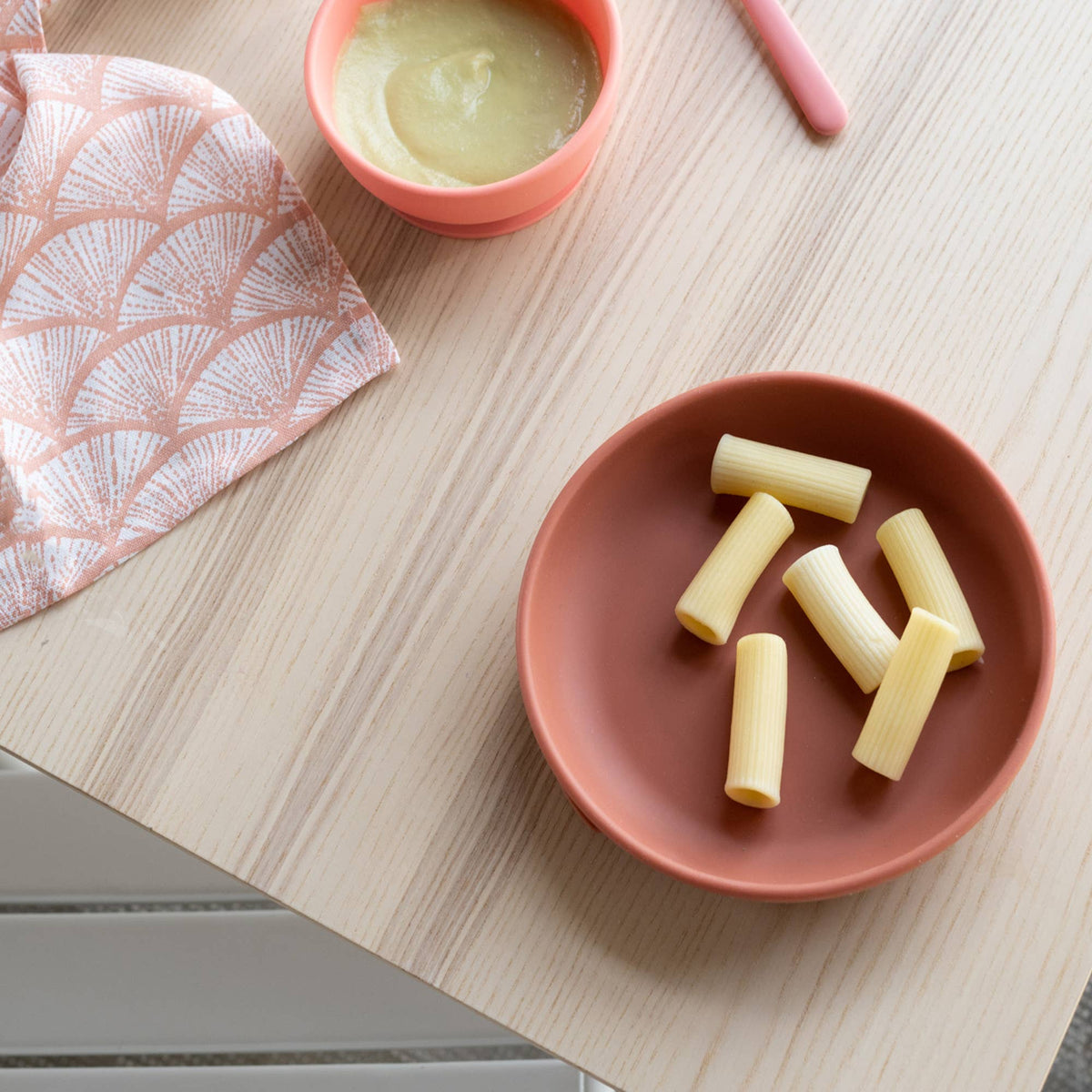 Red bowl with pasta on a wooden table