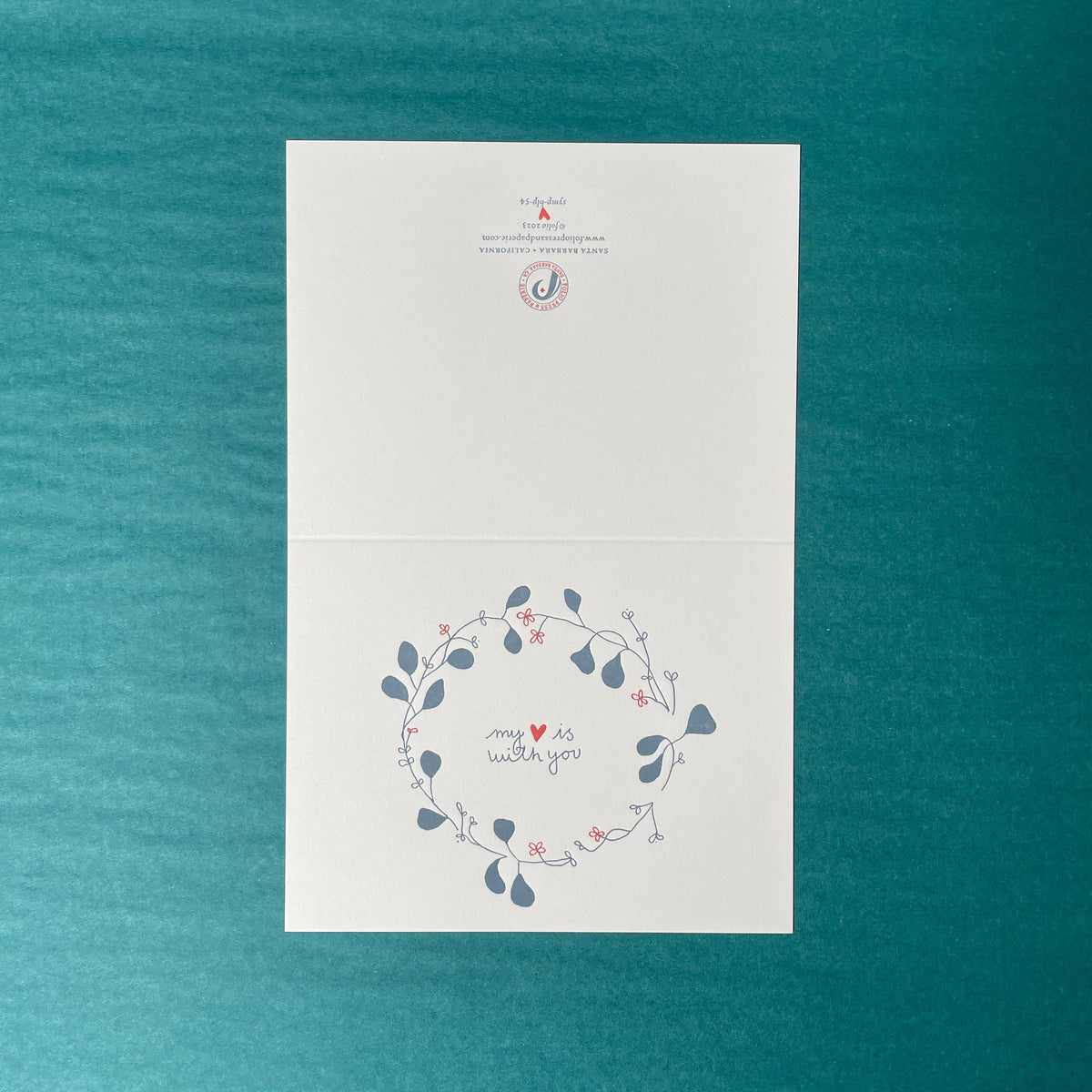 White card with floral design and text on a teal background