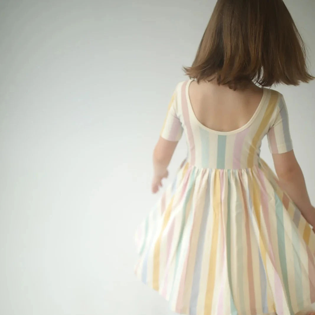 Child wearing a pastel striped dress with a white background