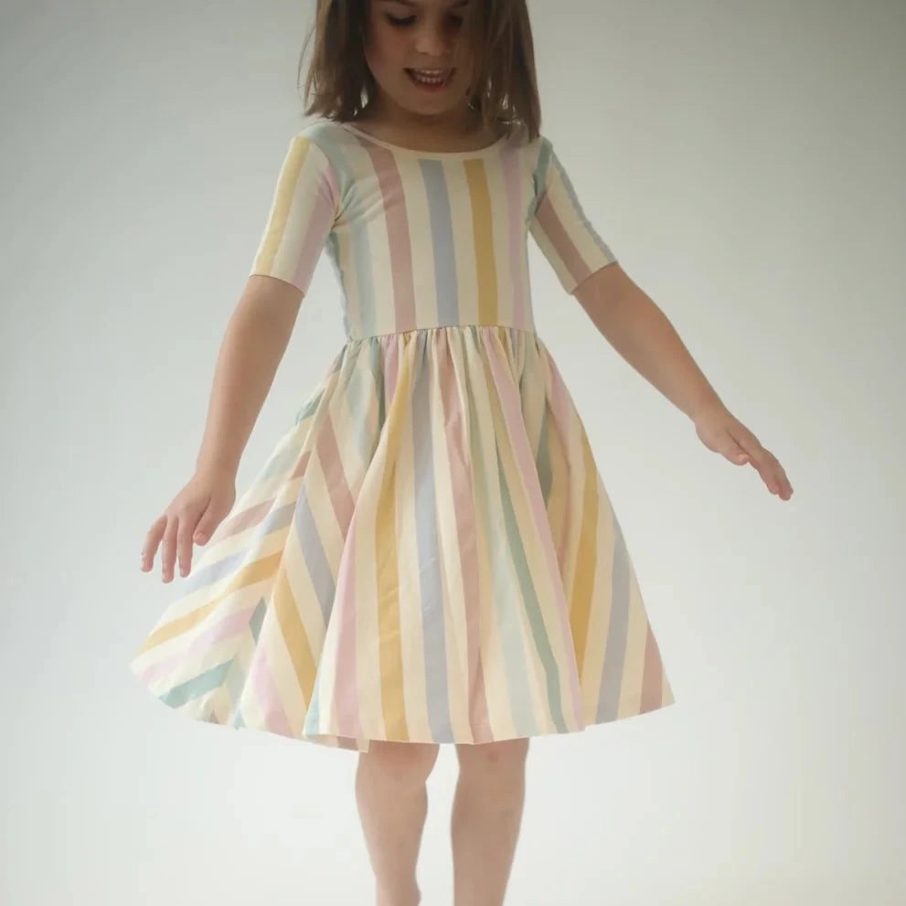 Child wearing a pastel striped dress with a white background