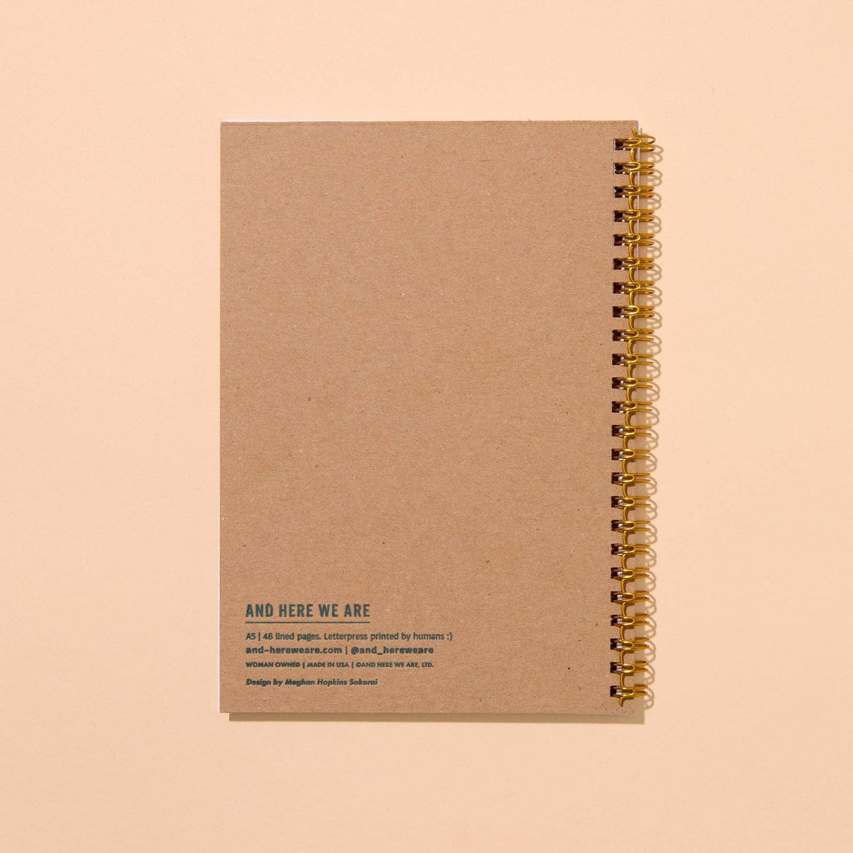 Brown notebook with gold spiral binding on a beige background