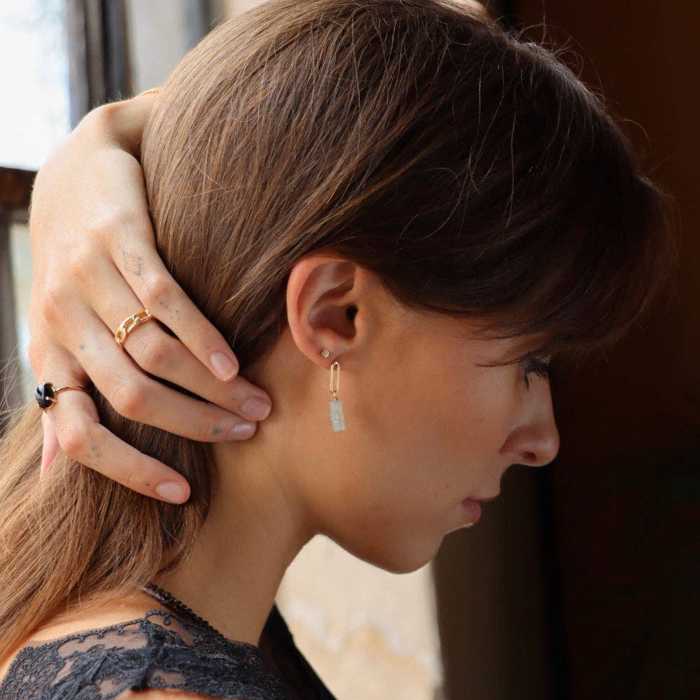 Woman wearing gold earrings with a blurred background