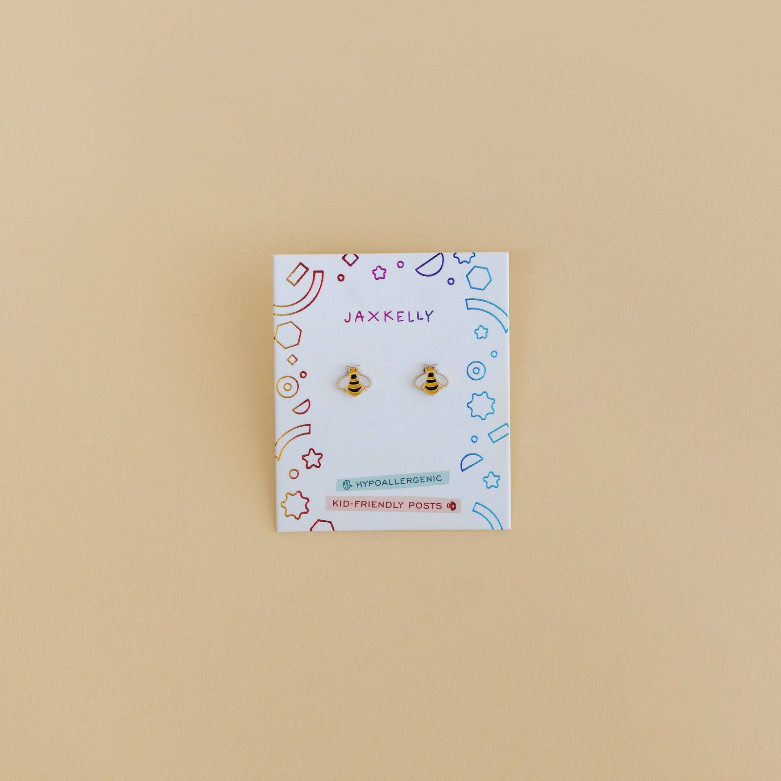 Pair of gold bee-shaped earrings on a Jax & Elle branded card against a beige background