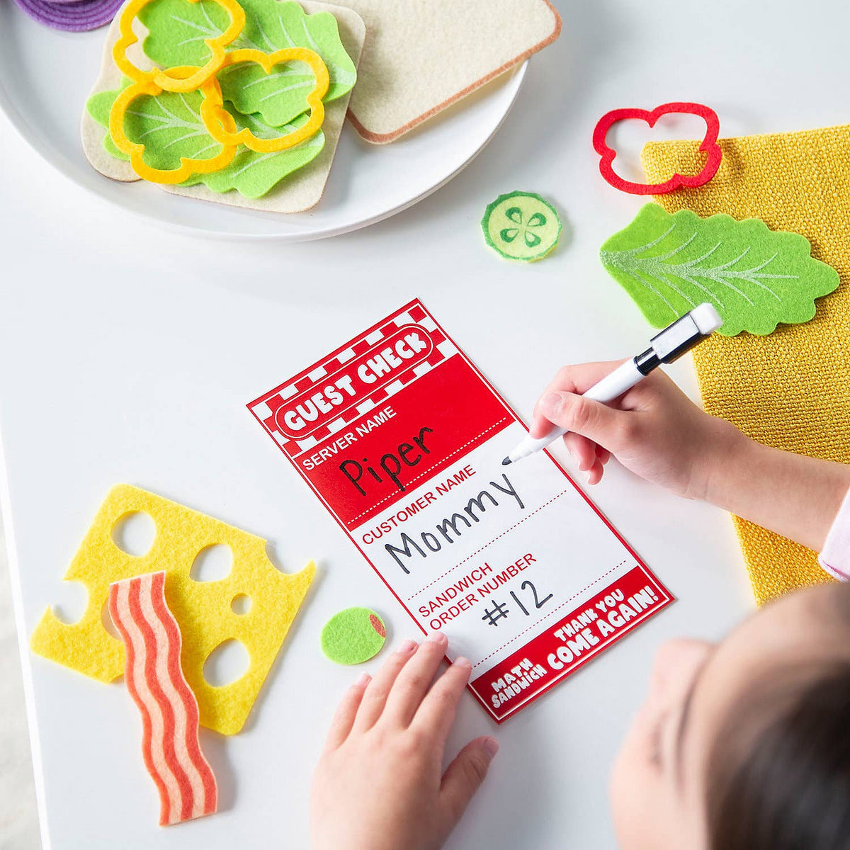 Child's hands interacting with a sandwich-making station and a sign with 'Mommy' written on it.