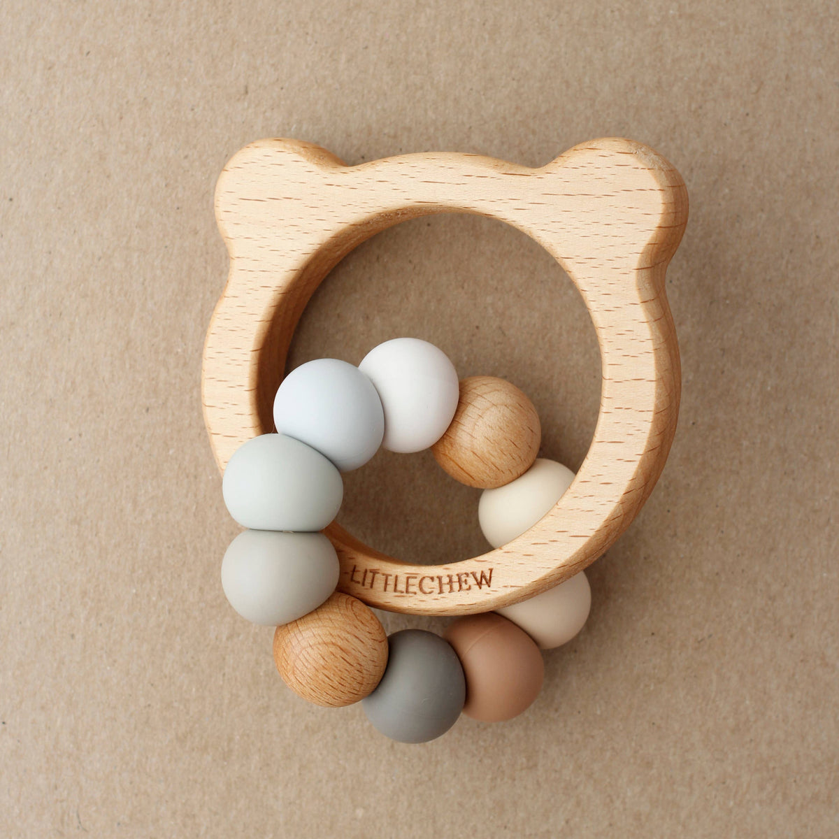 Wooden teething ring with colorful beads on a beige background