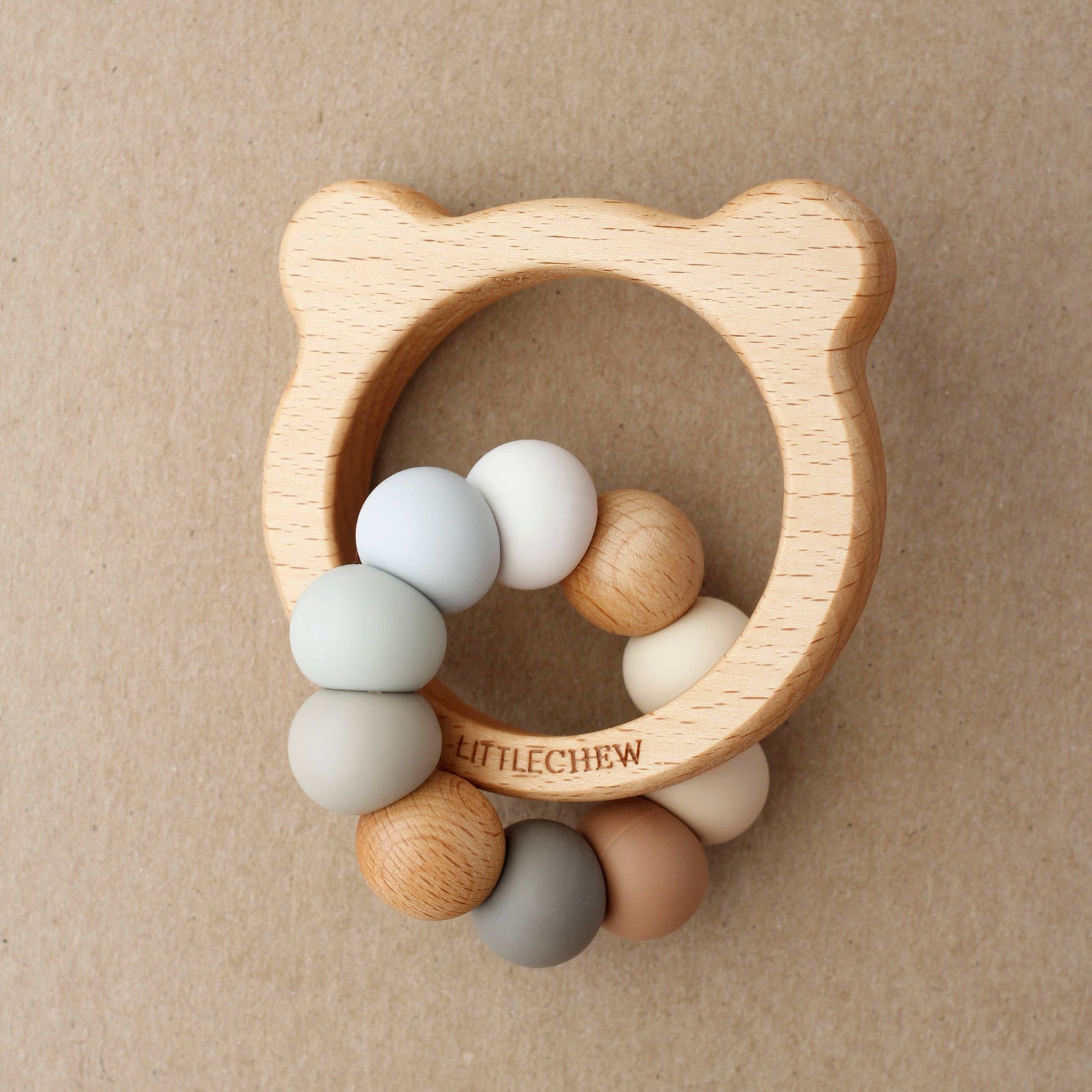 Wooden teething ring with colorful beads on a beige background