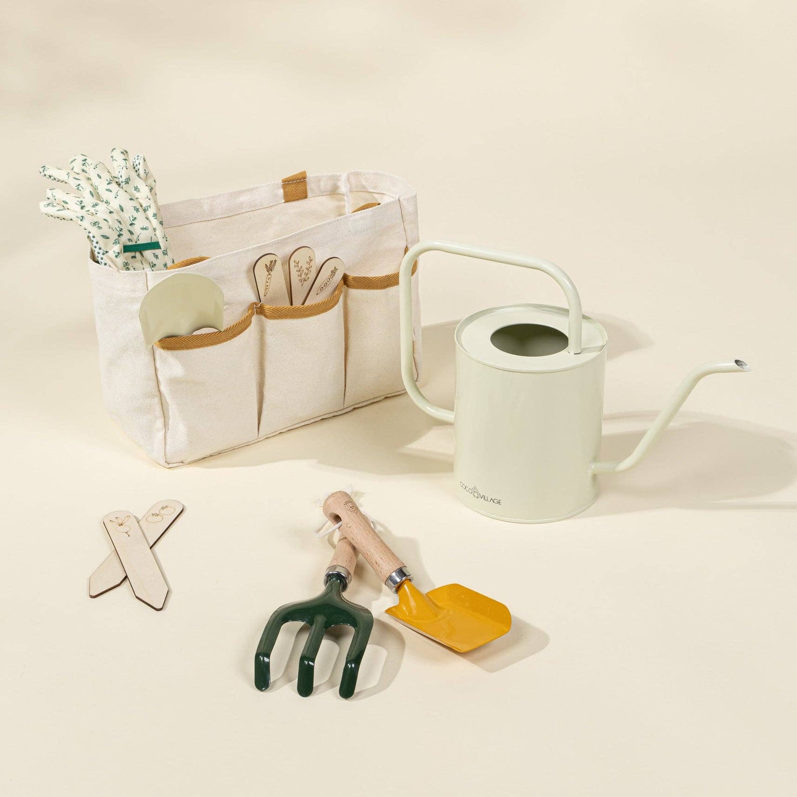 Gardening tools including a watering can, trowel, and fork on a light beige background.