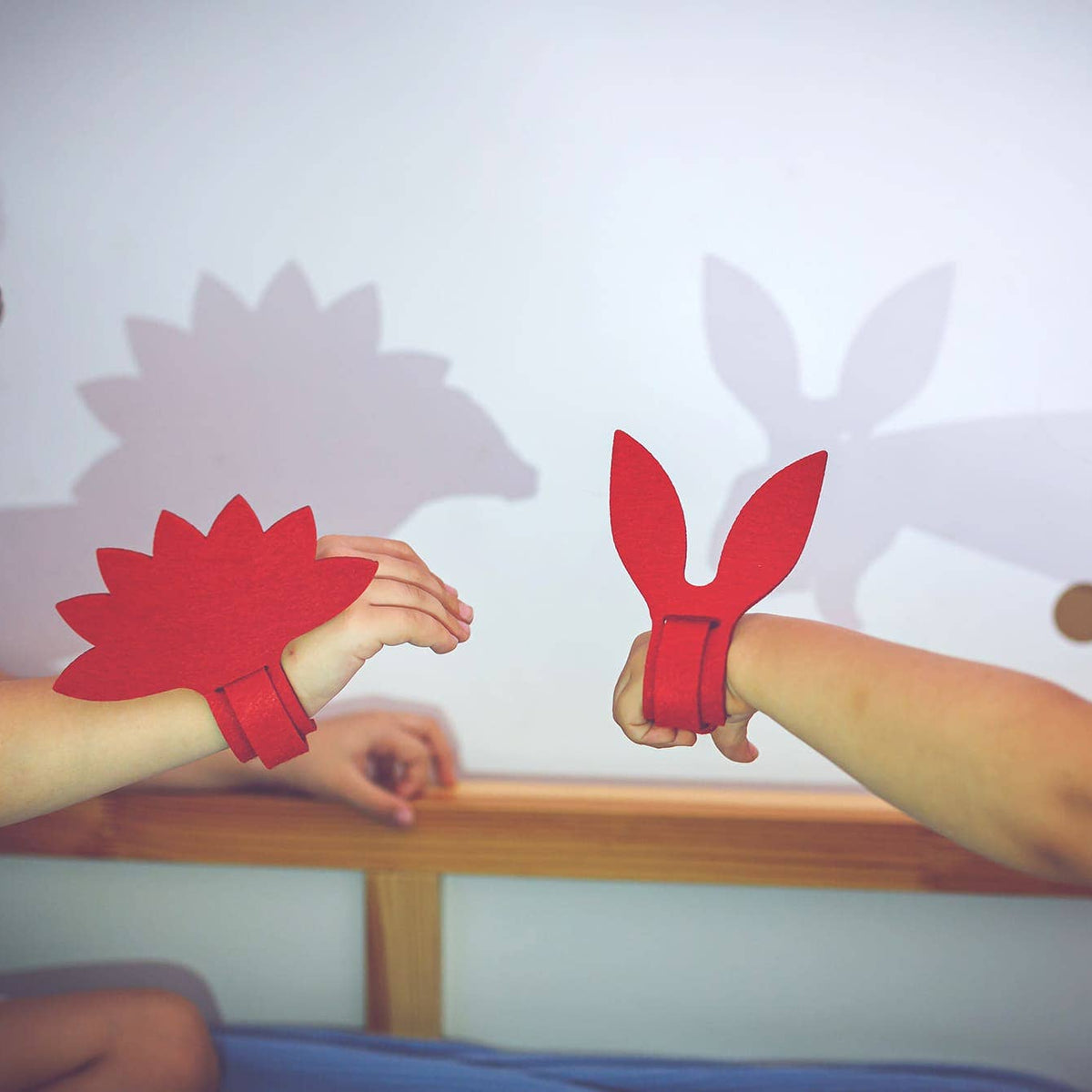 Two children with red shadow puppet arm bands sitting across a table.